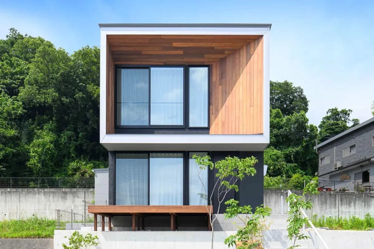緑豊かな背景に建つ木目と黒のコントラストが美しい住宅