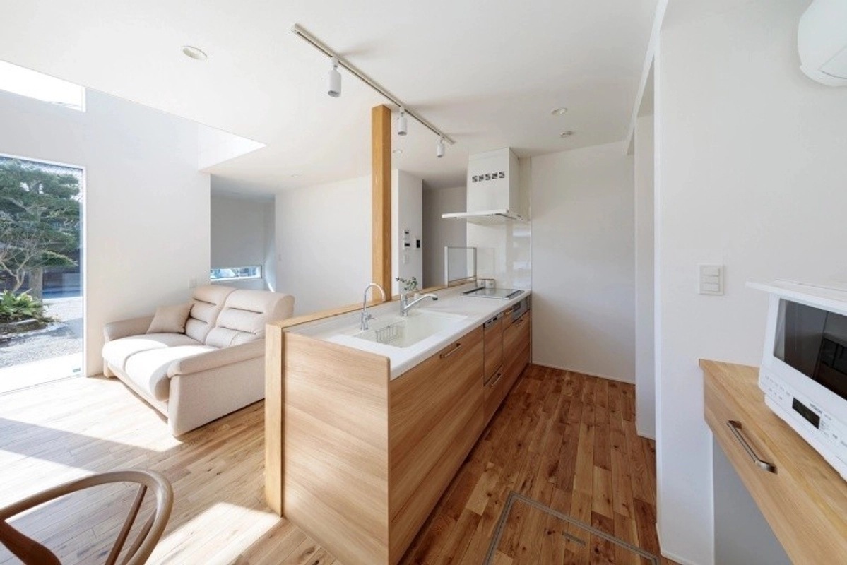 大きな窓から光が差し込む、木目調の対面キッチンと明るいリビング