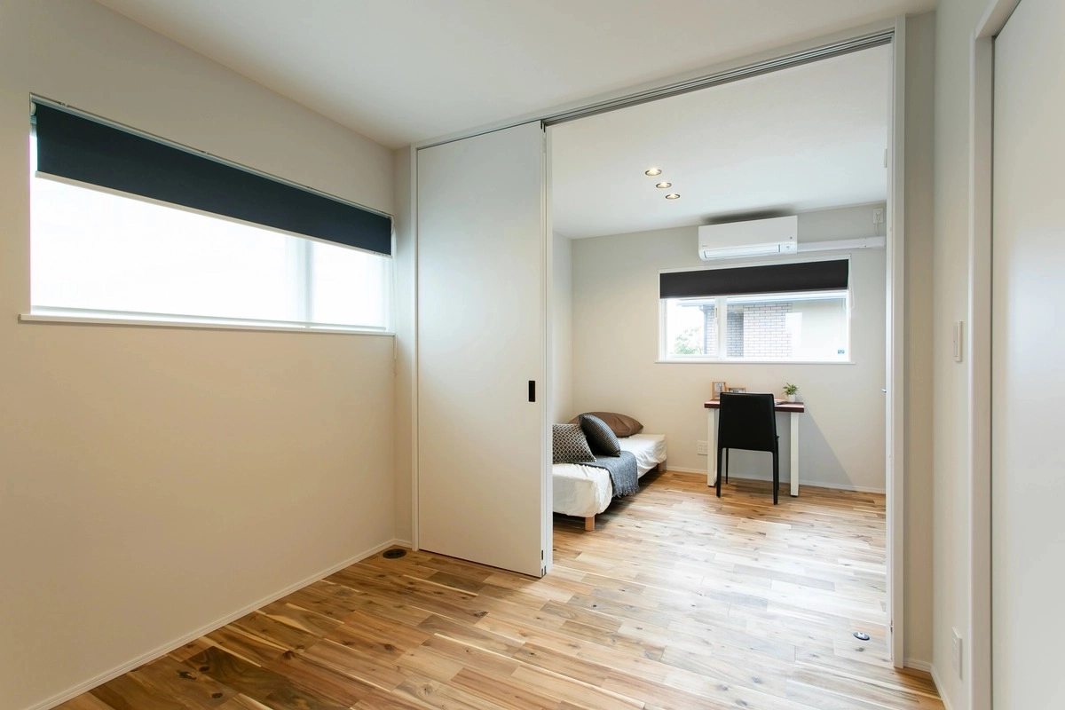引き戸で仕切られた無垢フローリングの洋室と個室