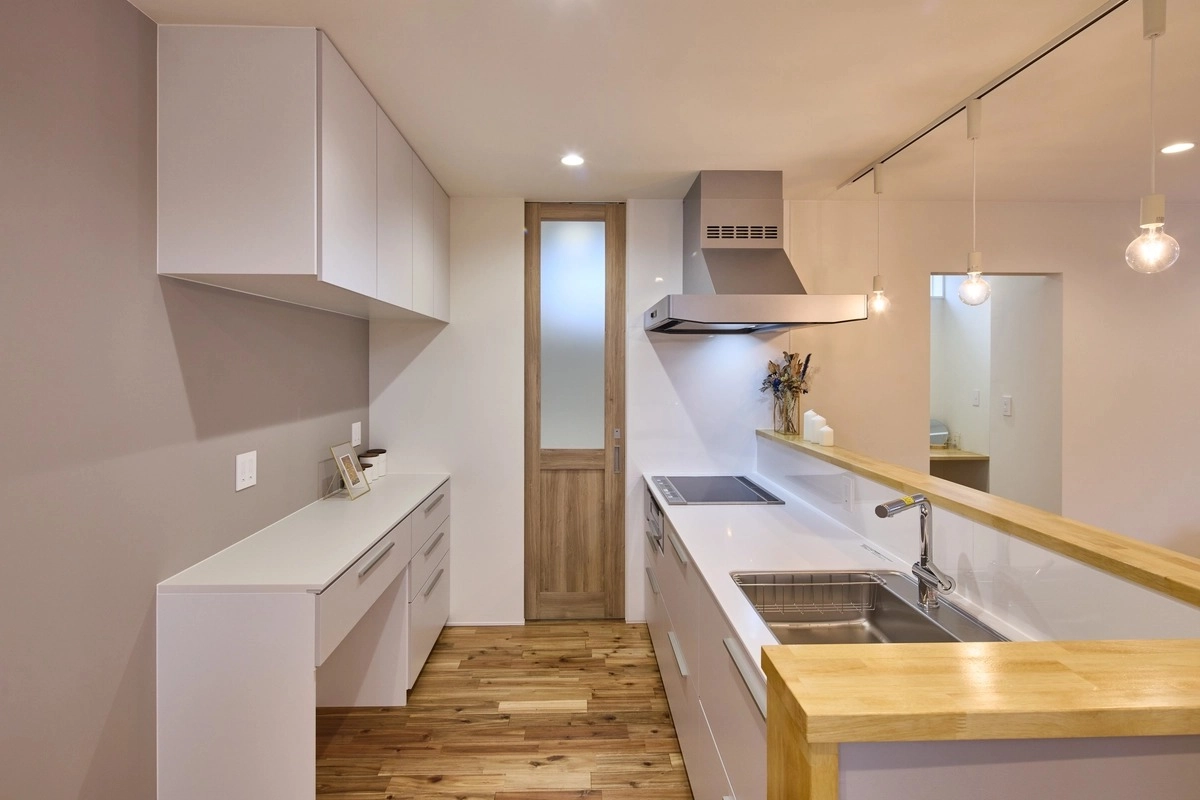 木製のカウンターと白い棚を設えた清潔感のあるキッチン