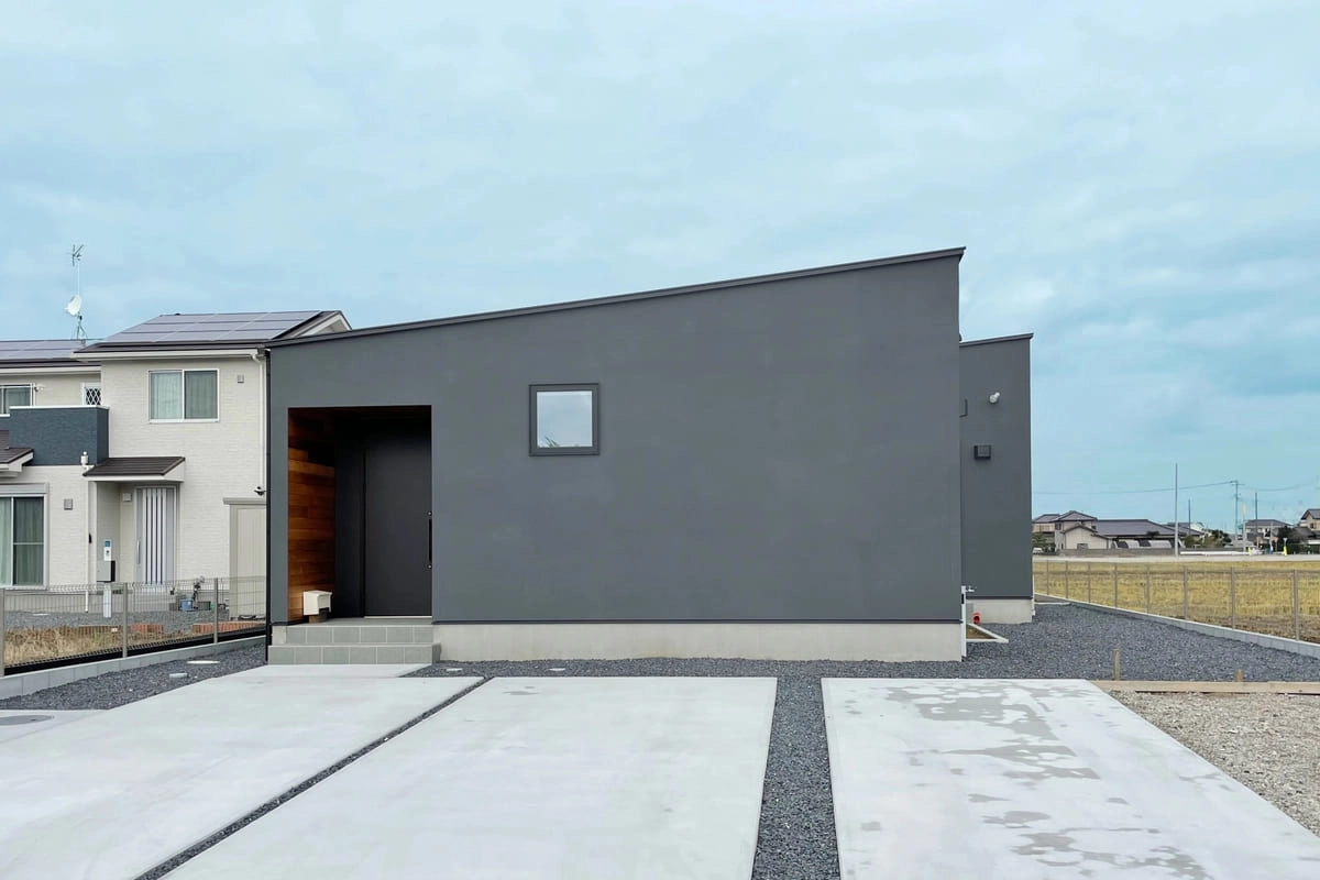 片流れ屋根が特徴的なグレーの塗り壁の外観