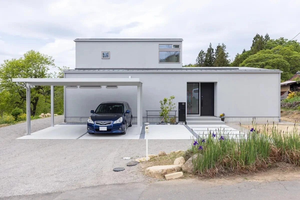 カーポートのあるグレーの住宅と花壇のアプローチ