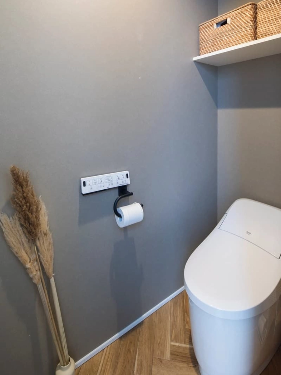 グレーの壁にヘリンボーンの床がアクセントのトイレ