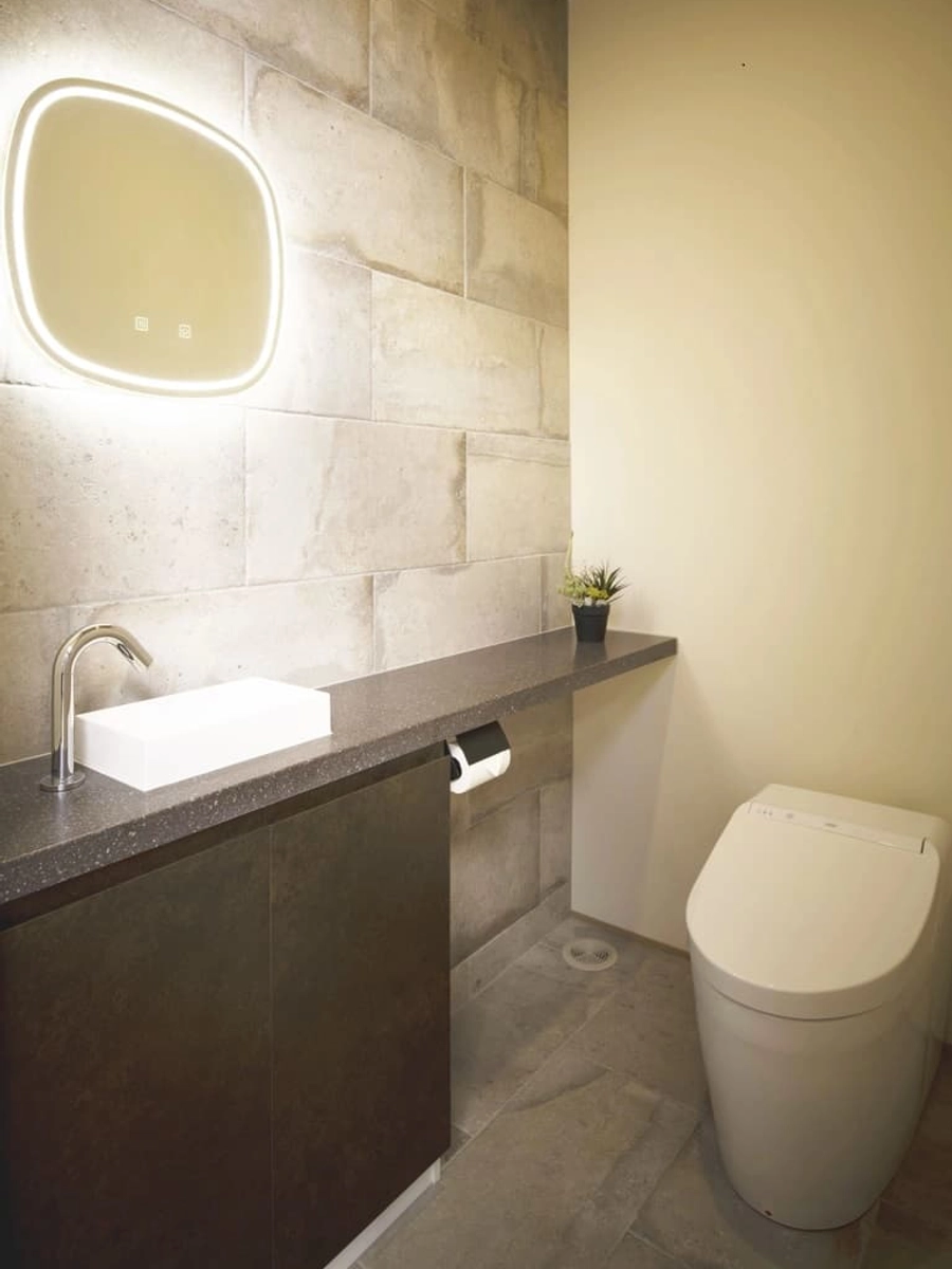 石目調クロスと床の落ち着いた色合いのトイレ