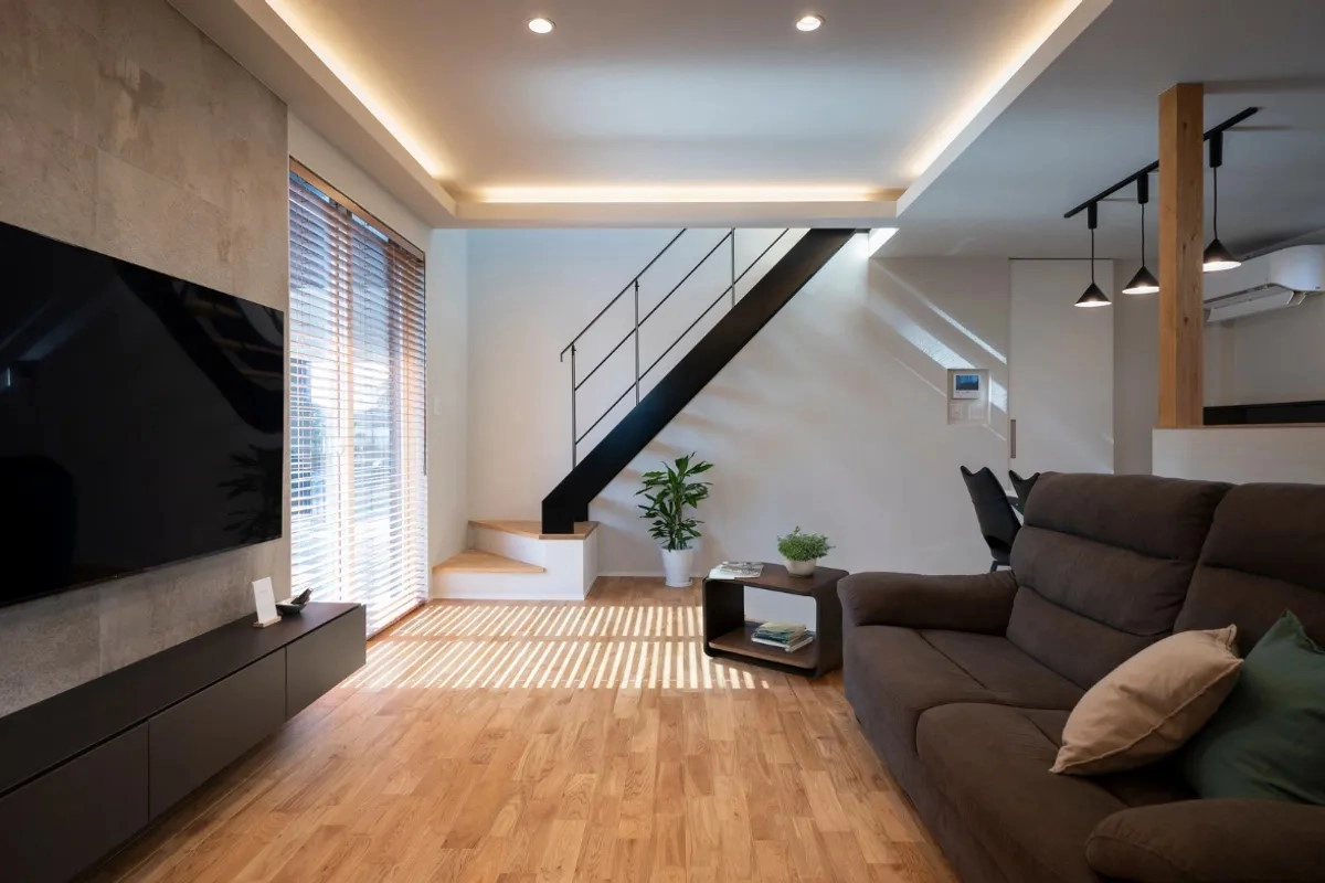 吹き抜け階段と大きな窓があり間接照明が温かく灯るオーク材フローリングのリビング