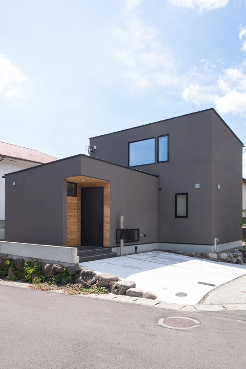 木材のアクセントがあるブラウンの箱型住宅の外観