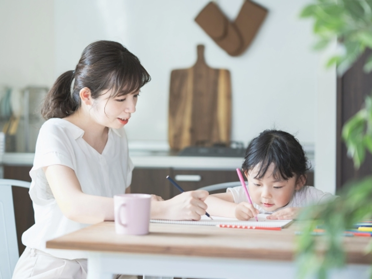 ダイニングテーブルで勉強する子供と見守る母
