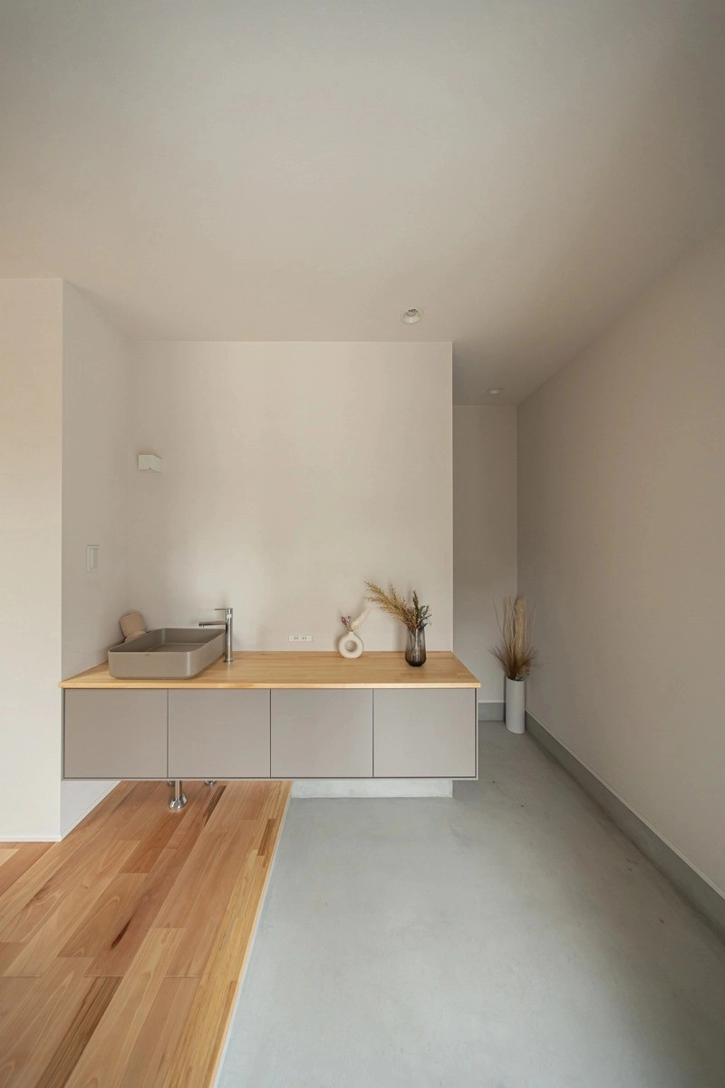 木製カウンターにスクエア洗面ボウルを置いたミニマルな洗面台