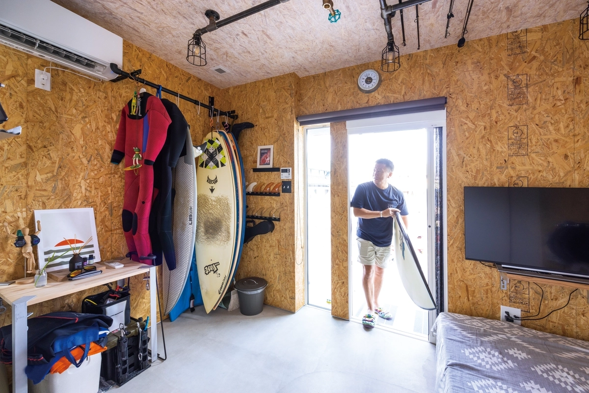 サーフボードを吊るして収納できる、天井高のあるモルタル仕上げの土間趣味室
