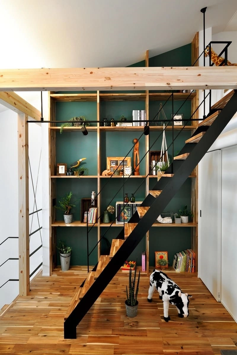 緑の壁と棚、鉄骨階段のある空間