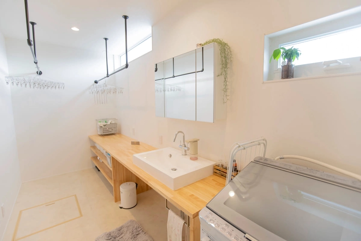 木のカウンター洗面台とアイアンの物干しがある洗面脱衣室