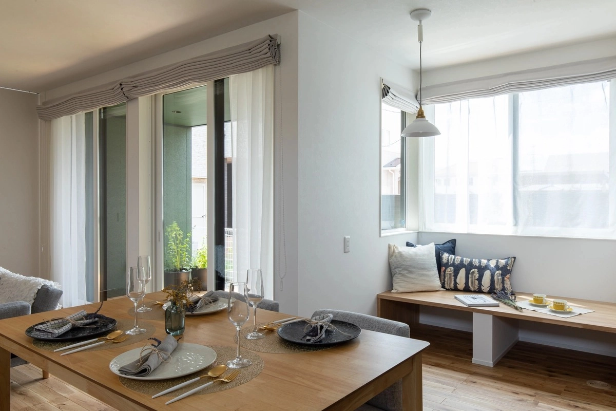 窓辺のベンチ収納と食事の準備が整った木製ダイニング