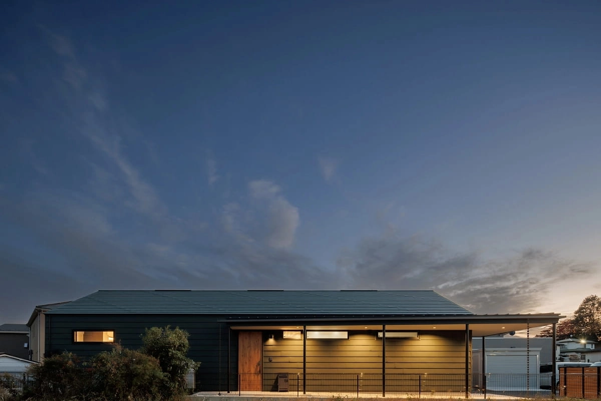 夕暮れの空と深い軒のある黒い外壁の平屋