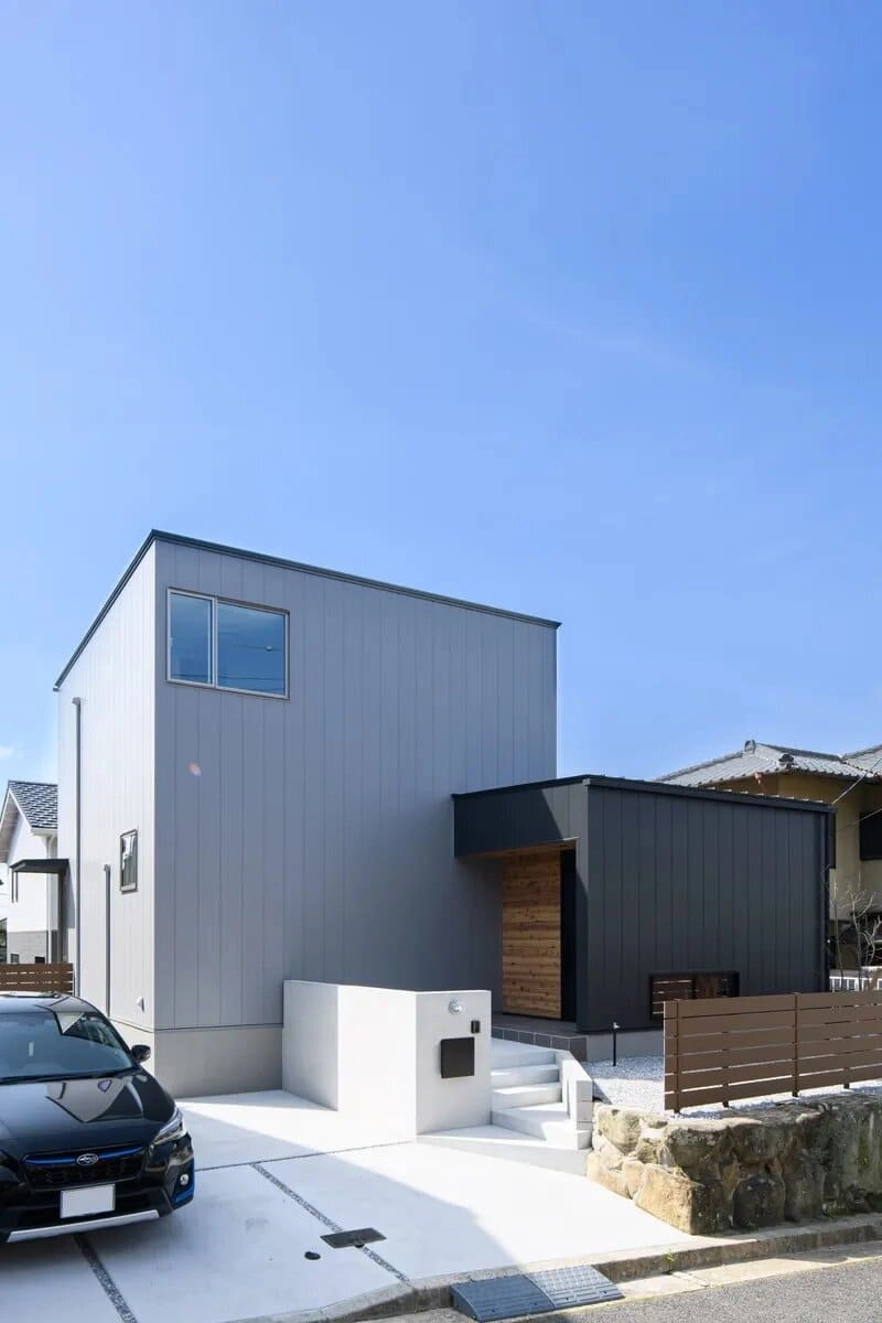 グレーと黒のツートンカラーの住宅と白い門柱