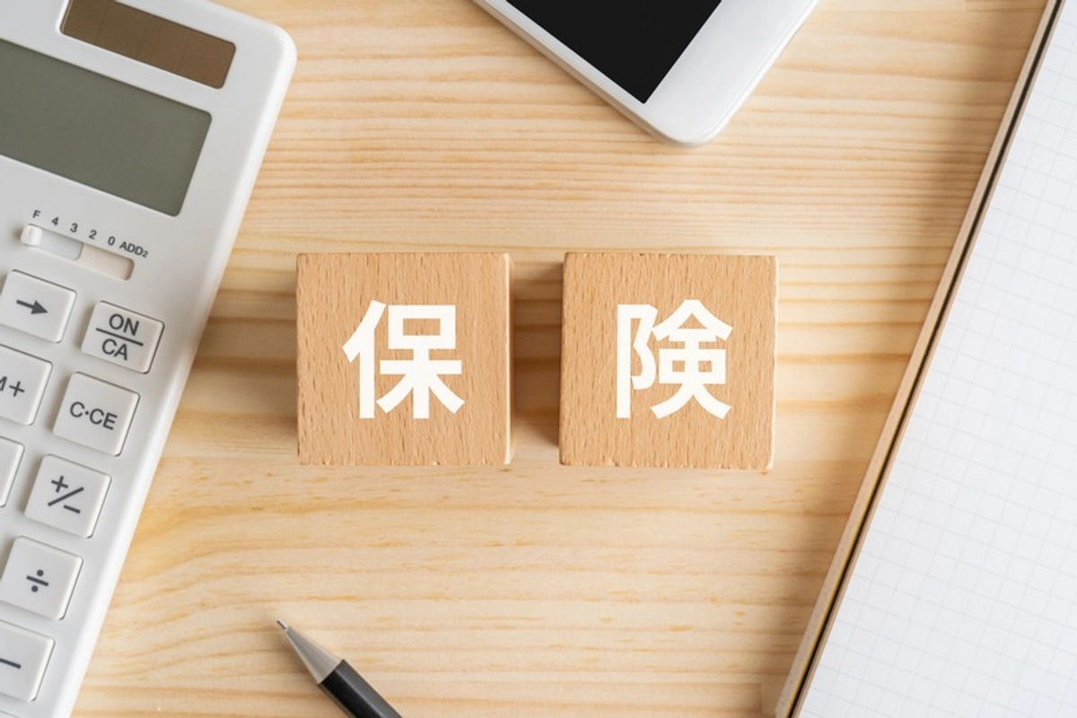 保険と書かれたブロックと電卓とボールペン