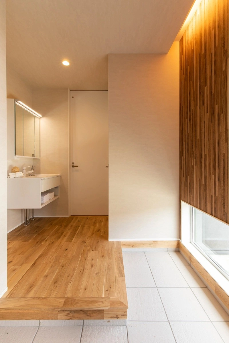地窓からの光が差し込む玄関ホールとシンプルな洗面ユニット