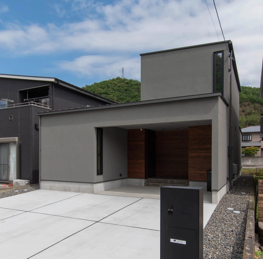 木製の玄関周りがポイントのグレーの家