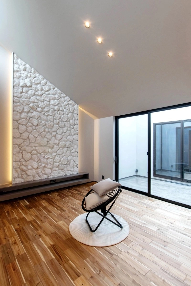 石積みのアクセントウォールと黒いチェアが置かれたリビング