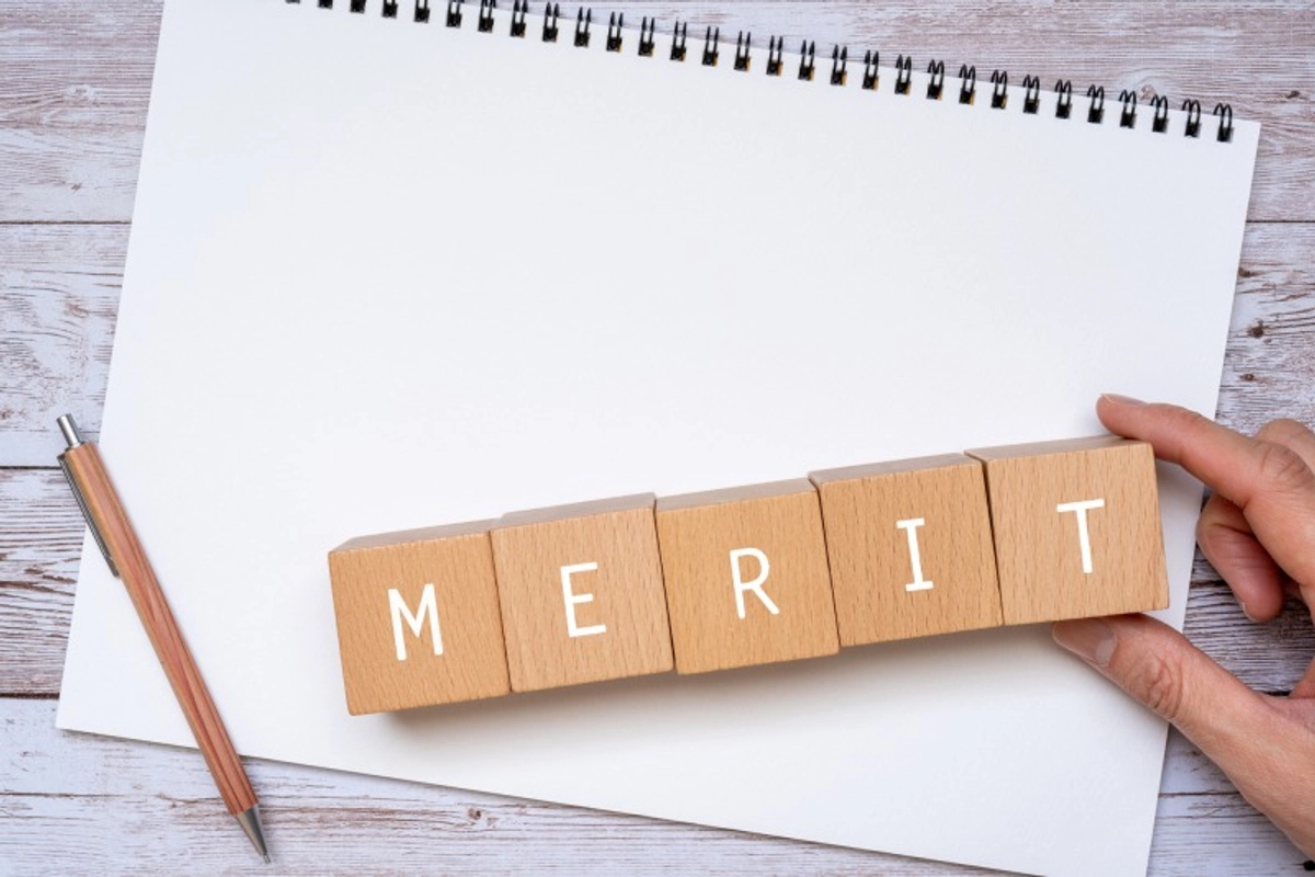 スケッチブックの上の「MERIT」と書かれた積み木