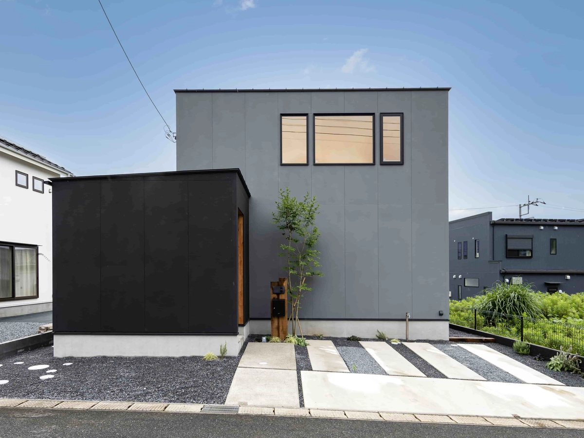 黒とグレーの外壁にシンボルツリーが映える外観