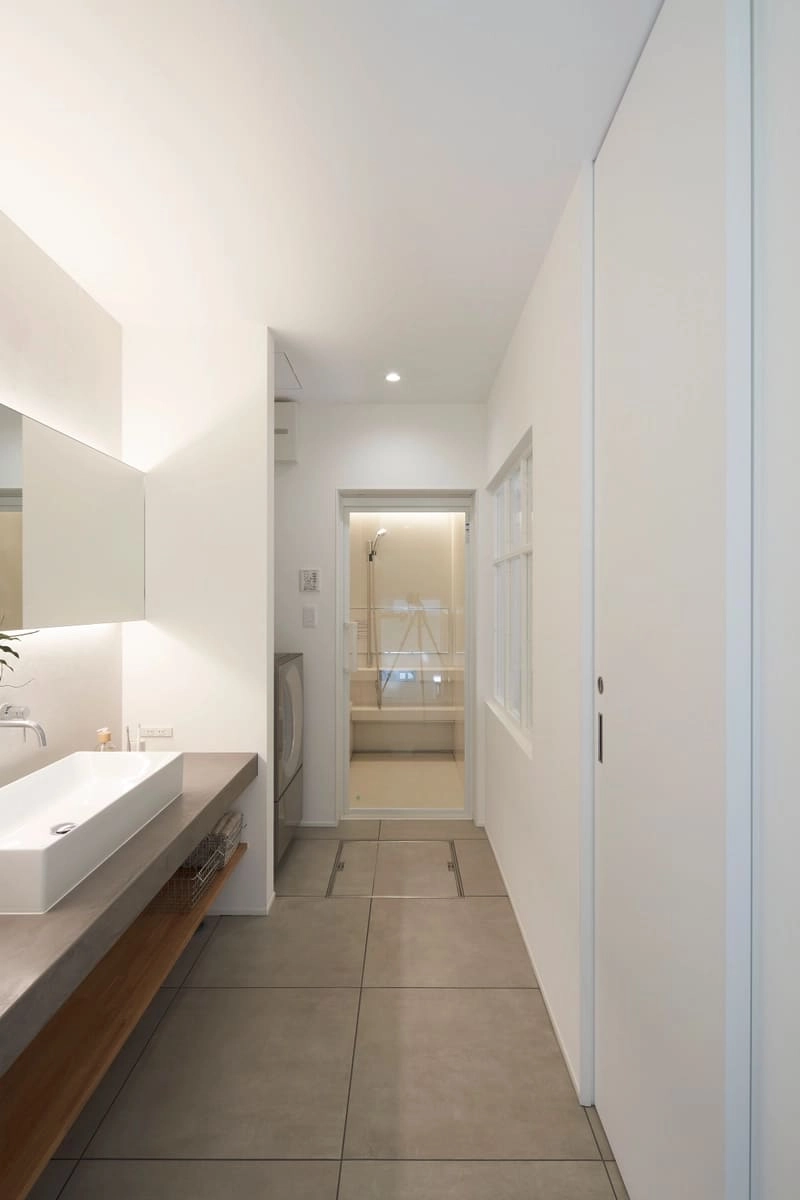 グレーのカウンター洗面台とタイル床のモダンな洗面脱衣室