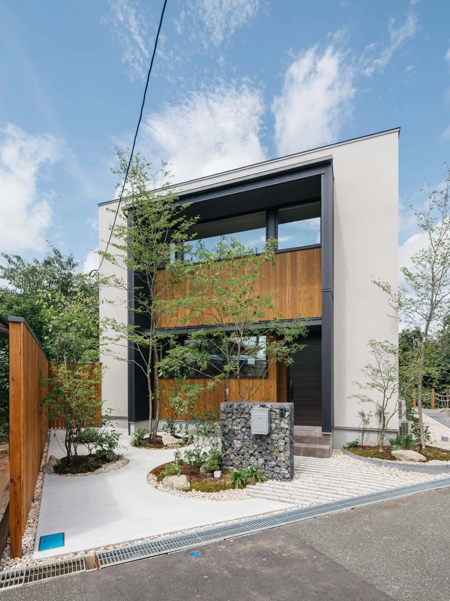 白と木目の外壁に植栽豊かな外観