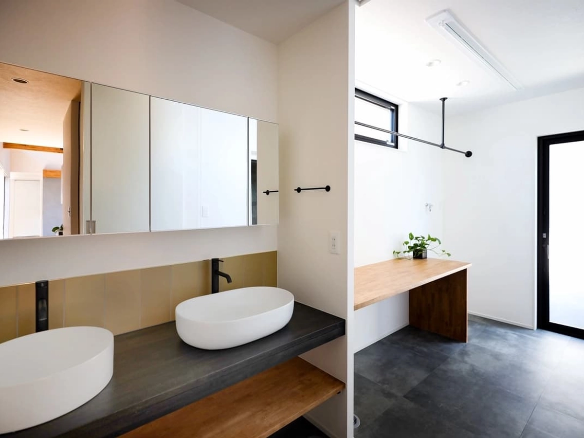 大きめのミラーと2台の洗面ボウルのある広々とした洗面ルーム