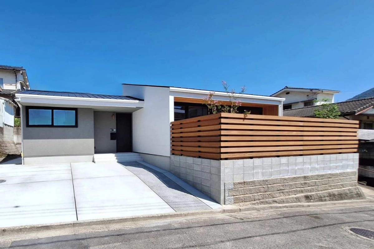 木製フェンスでプライバシーを確保した白い平屋