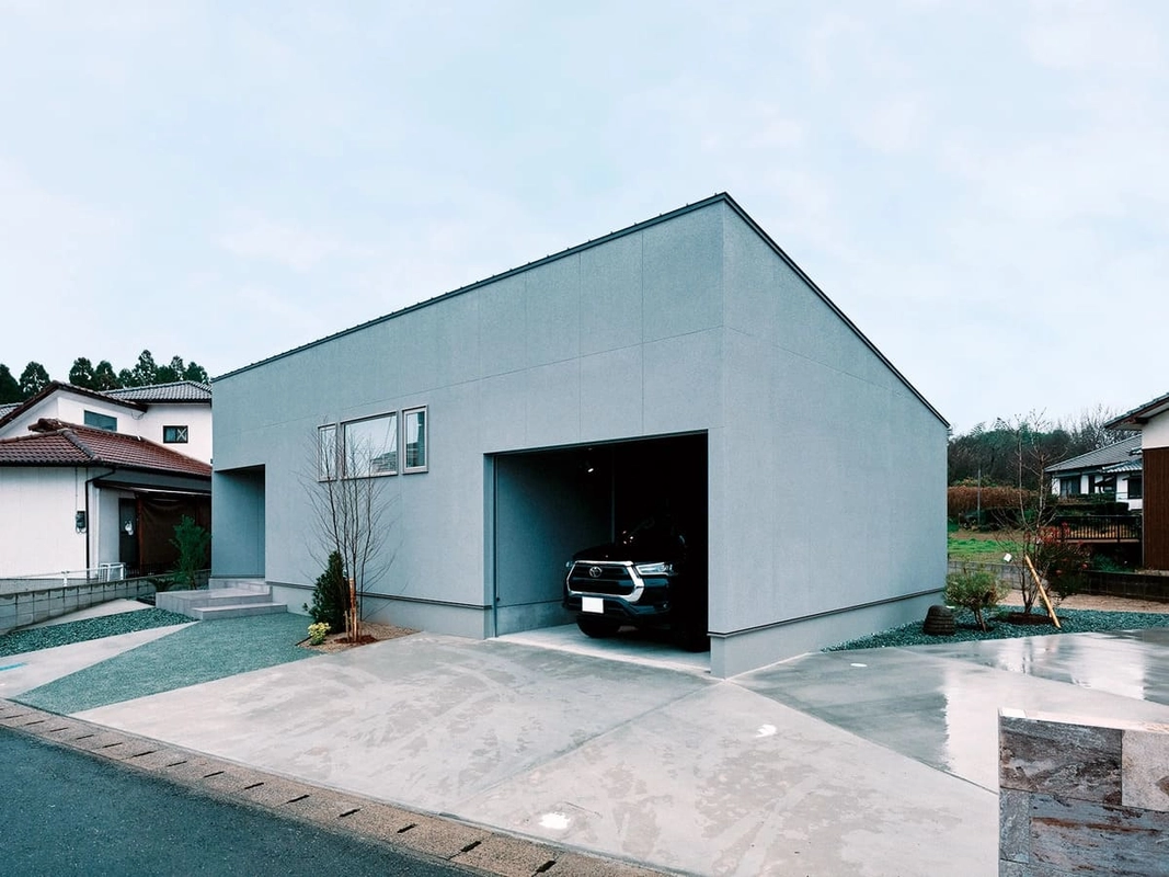 黒い車が停まるインナーガレージを備えたグレーの外壁の住宅