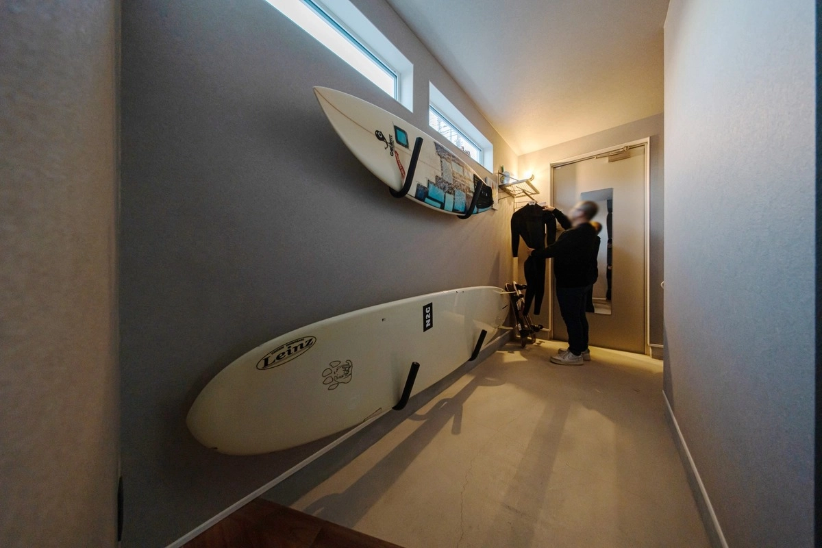 グレーの壁面にサーフボードを縦に並べて収納した土間空間