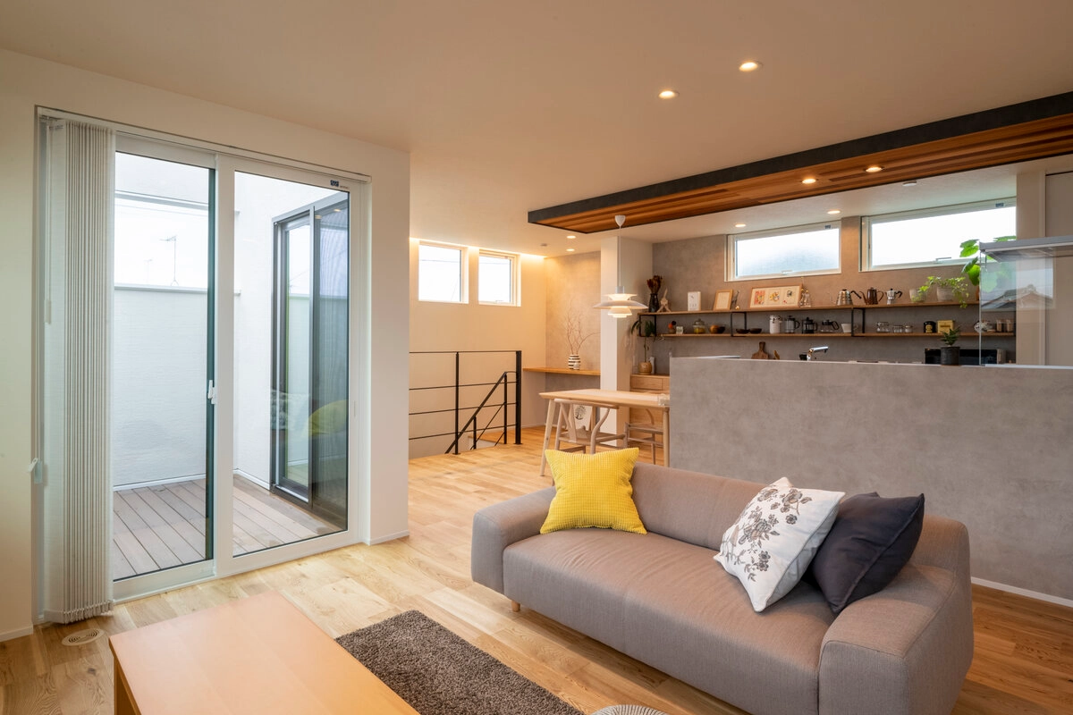 インナーバルコニーに繋がるグレーのソファがある明るいLDK