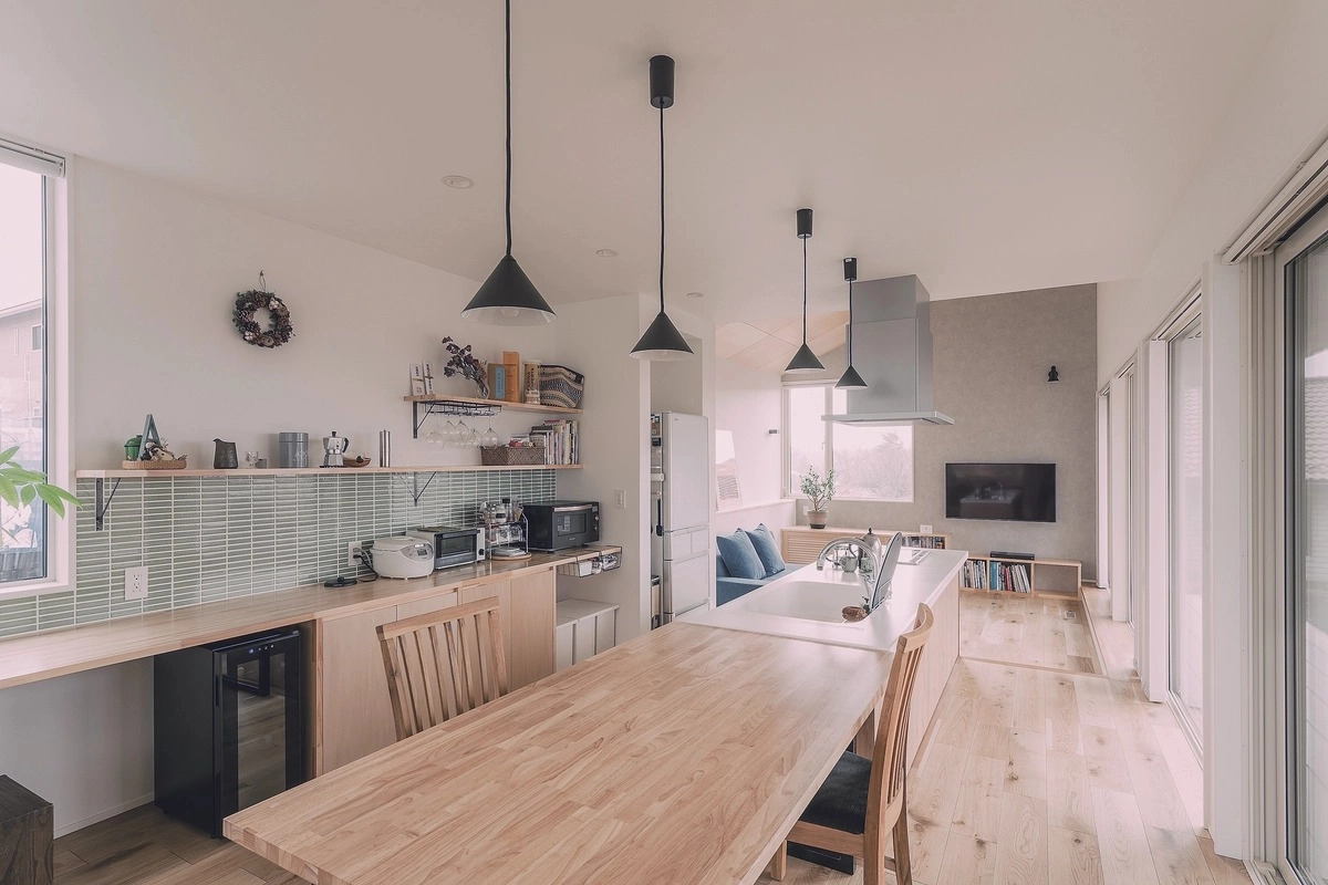 黒いペンダントライトが下がる木目天板の対面キッチン