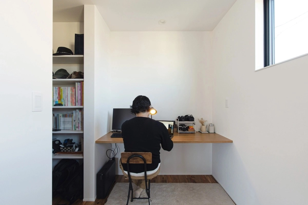 造作本棚が備え付けられた書斎でパソコン作業をする男性