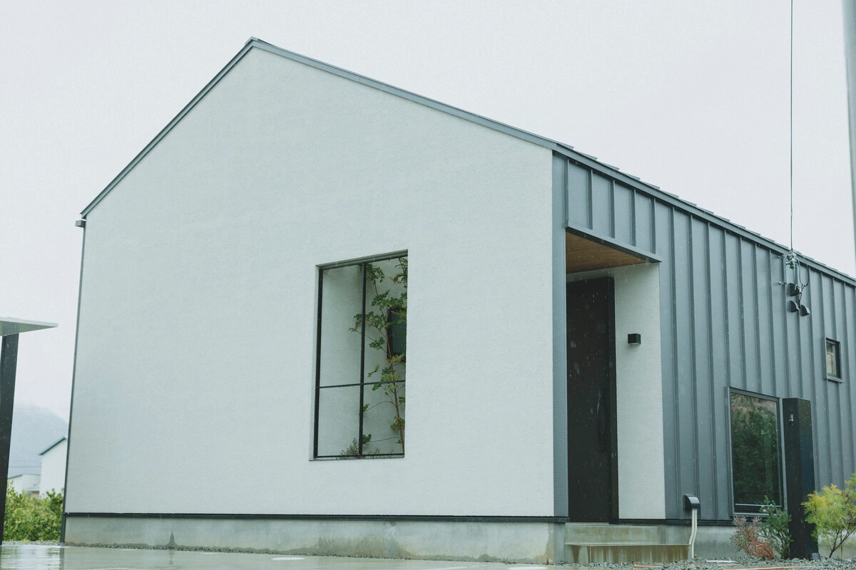 白い塗り壁とグレーのガルバリウムが調和するモダンな平屋