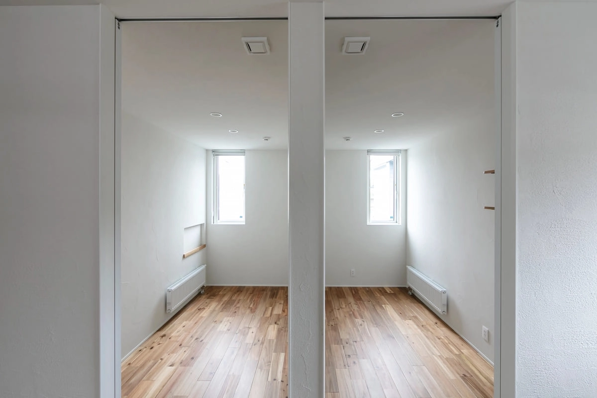 シンメトリーに配置された2つの小窓がある白い個室