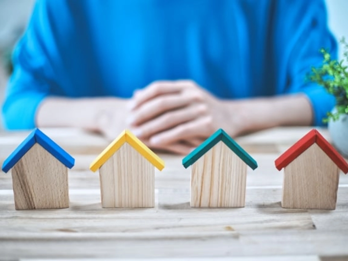 屋根の色が違う家の模型と相談している人の手