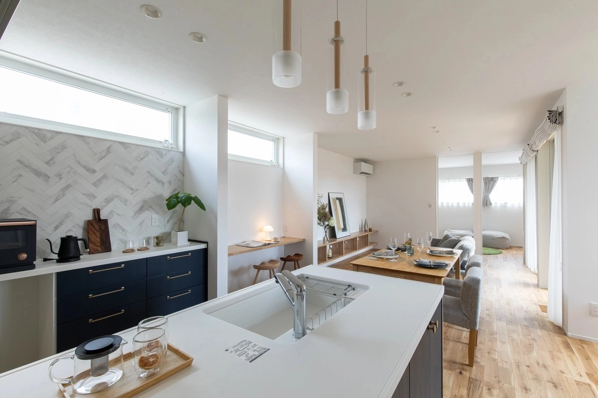 ヘリンボーン柄の壁とペンダントライトが並ぶ対面キッチン