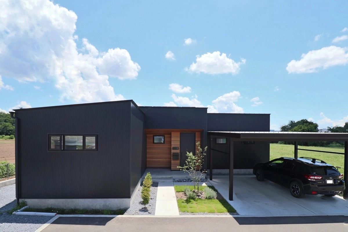 黒い外壁と木目の玄関ポーチが映える平屋の外観