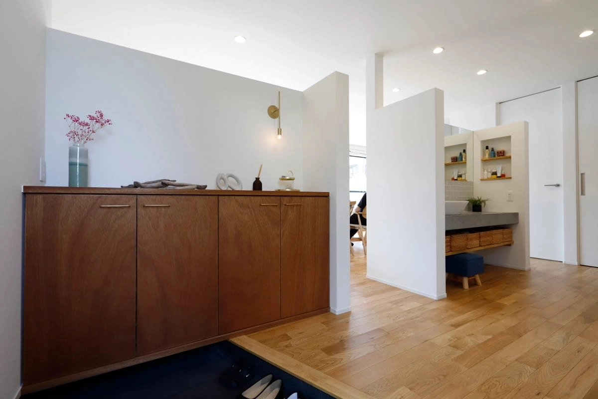 木製シューズボックスがある玄関と奥に見える洗面スペース