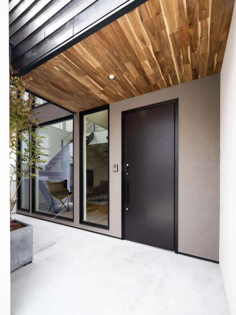 木仕上げの軒天と黒い扉の玄関