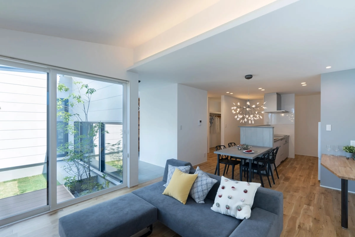 中庭の緑を望む大きな窓があるL字型ソファのリビング