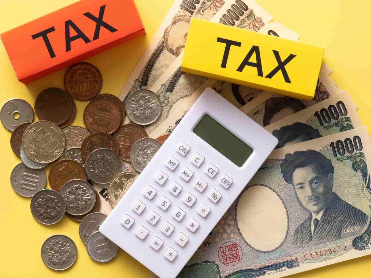 現金の上に置かれた電卓とタックスと書かれたブロック