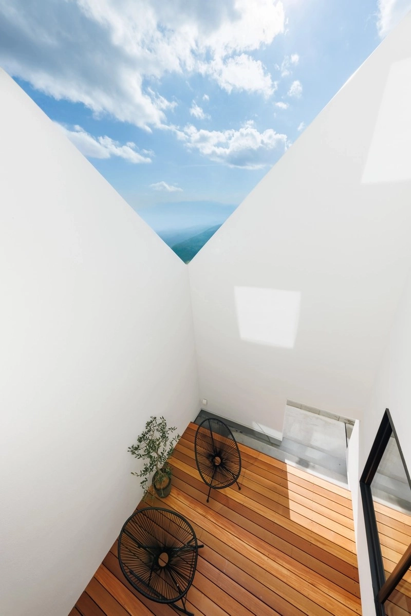 高い壁に囲まれたウッドデッキの中庭から見上げる青空と山並み