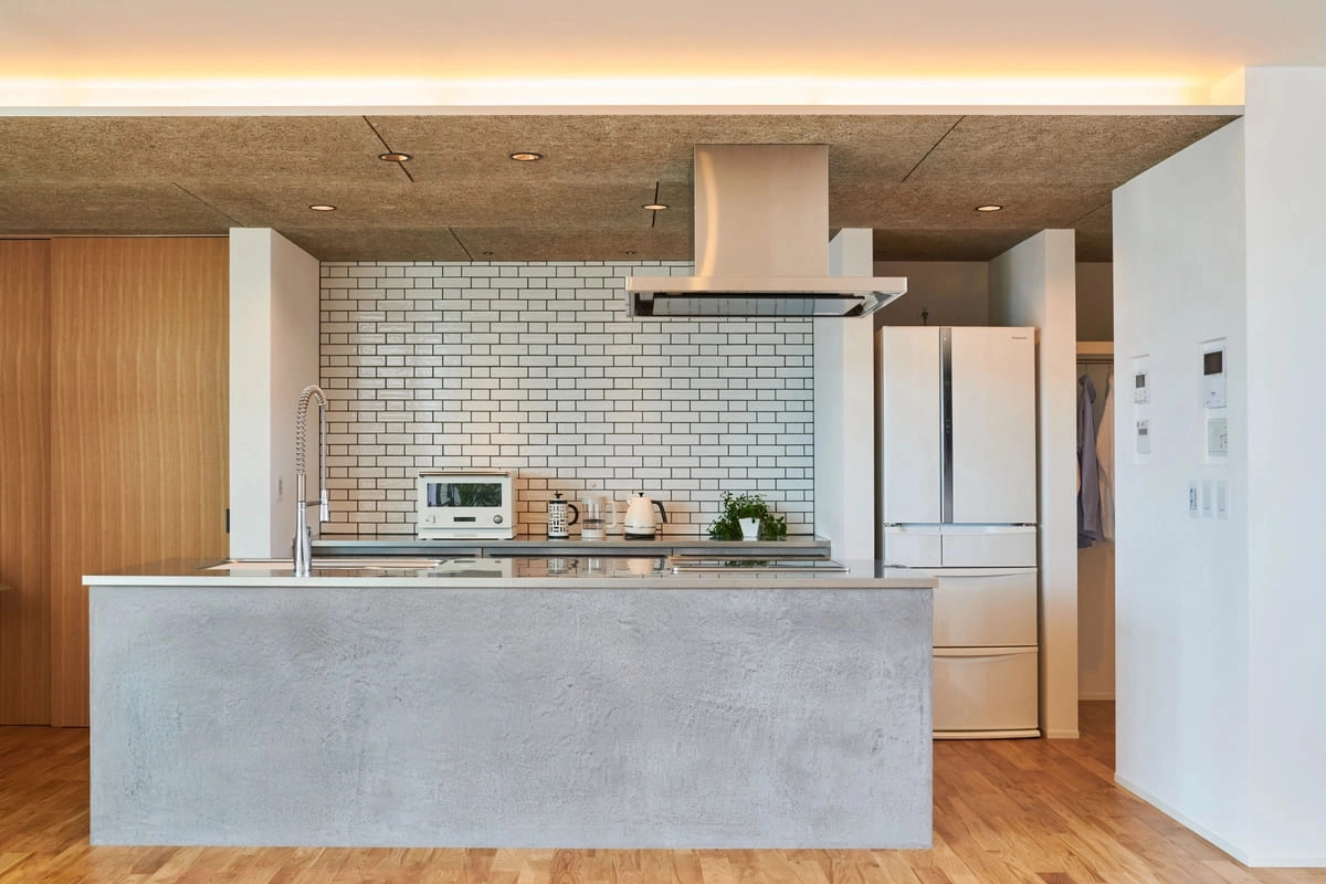 グレーのアイランドキッチンと白いタイル壁が特徴的な空間