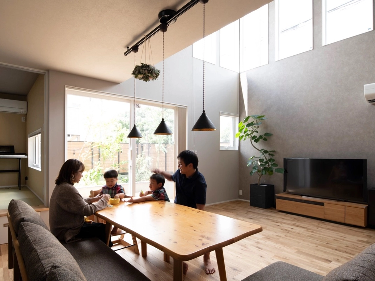 大きな吹き抜けと縦長の窓がある明るいリビング