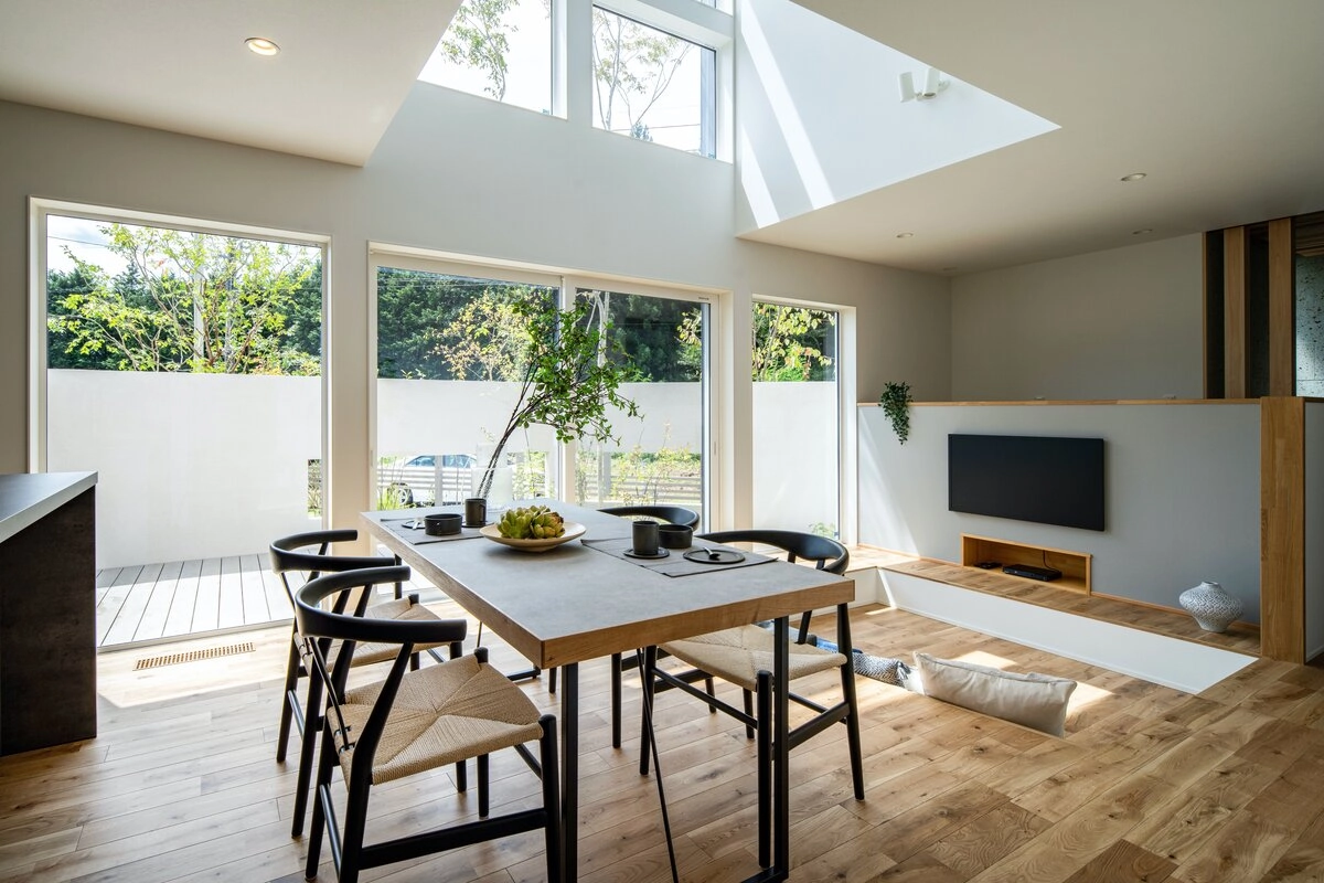 吹き抜けと大きな窓が開放的なLDKにある一段下がったダウンリビングとグレーの食卓