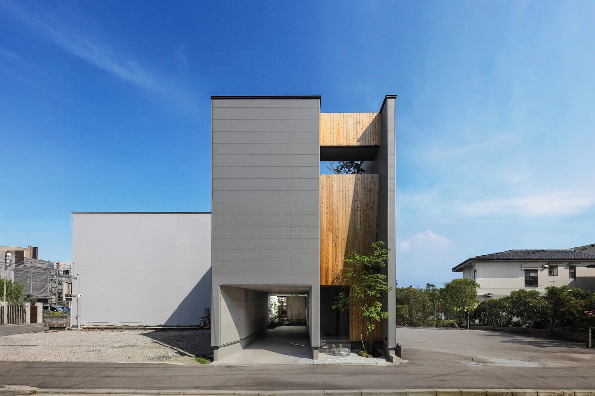 青空の下に立つグレーと木目のモダンな建物
