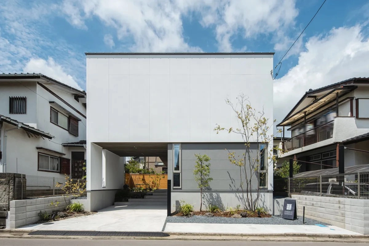 白とグレーのコントラストが美しいビルトインガレージを備えた2階建てのモダンな外観