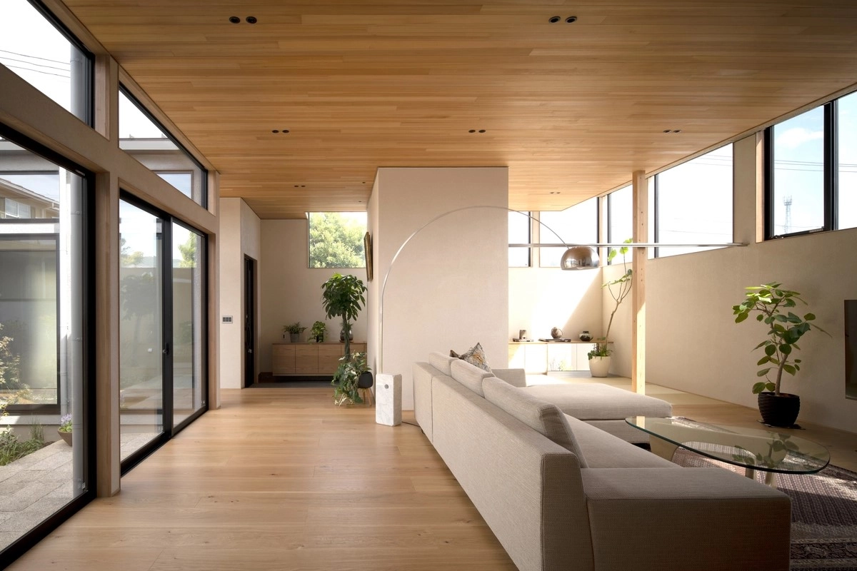 木の天井と床に囲まれた広い空間に大きな窓から光が差し込む平屋風のLDK