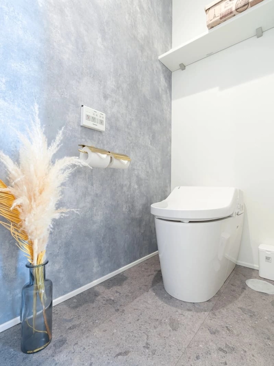 グレーと白のクロスと石目調の床のトイレ